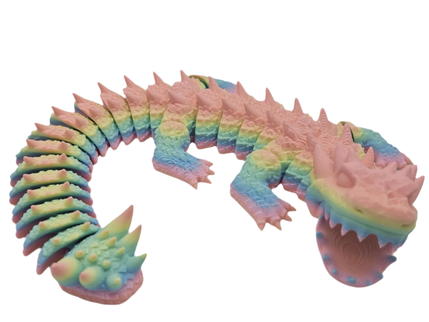 A rainbow-colored, articulated lizard is lying on a black surface. The lizard's tail curls upward and it opens its mouth.