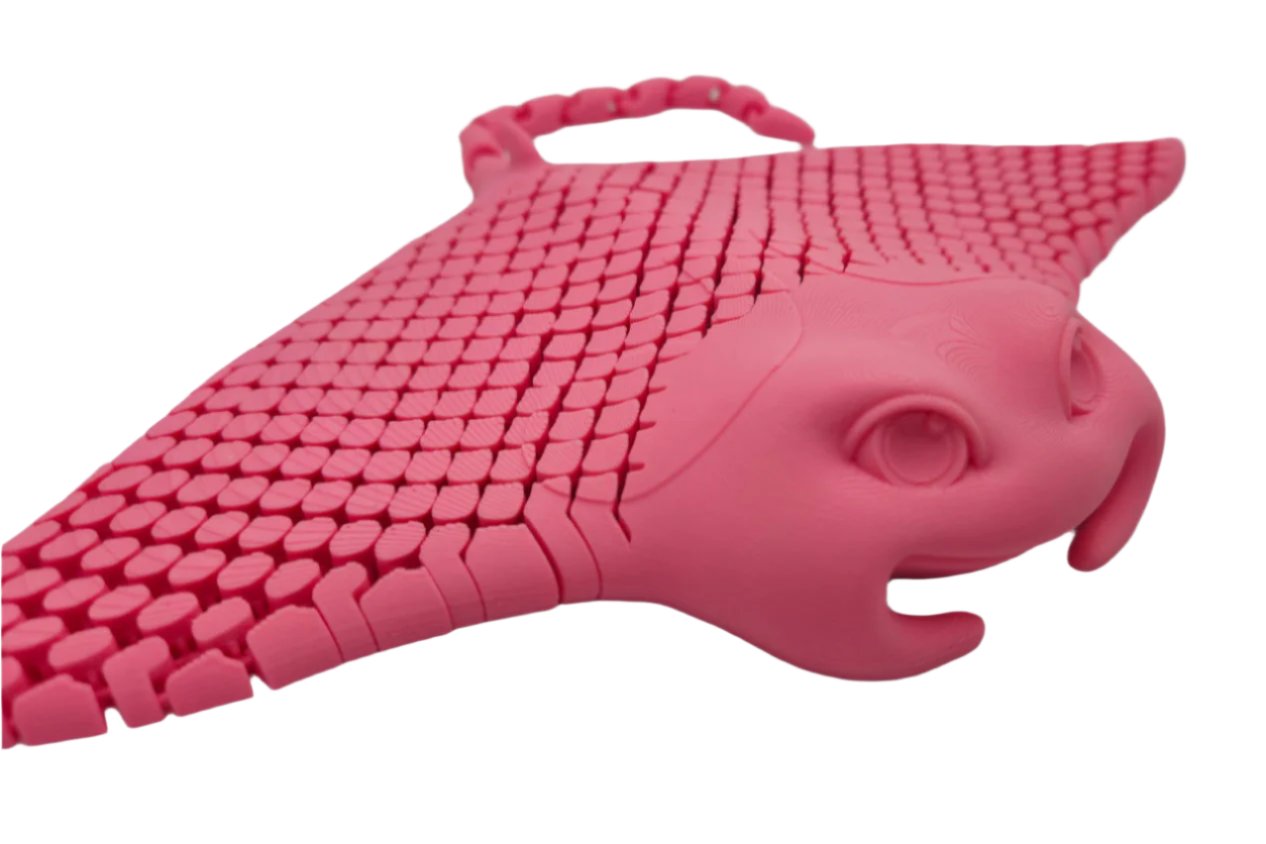 A pink, 3D-printed manta ray sits facing slightly right. Its dorsal surface has a tessellated pattern, and it floats against a black background.