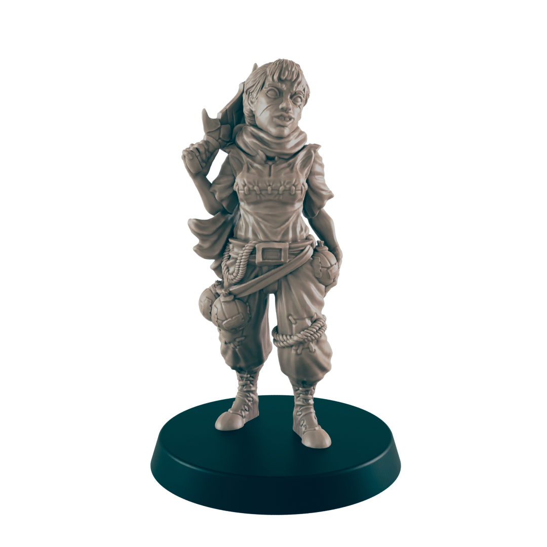 A miniature female figure, standing and holding a weapon, is displayed on a dark circular base. She wears a hooded top and loose trousers with pouches.