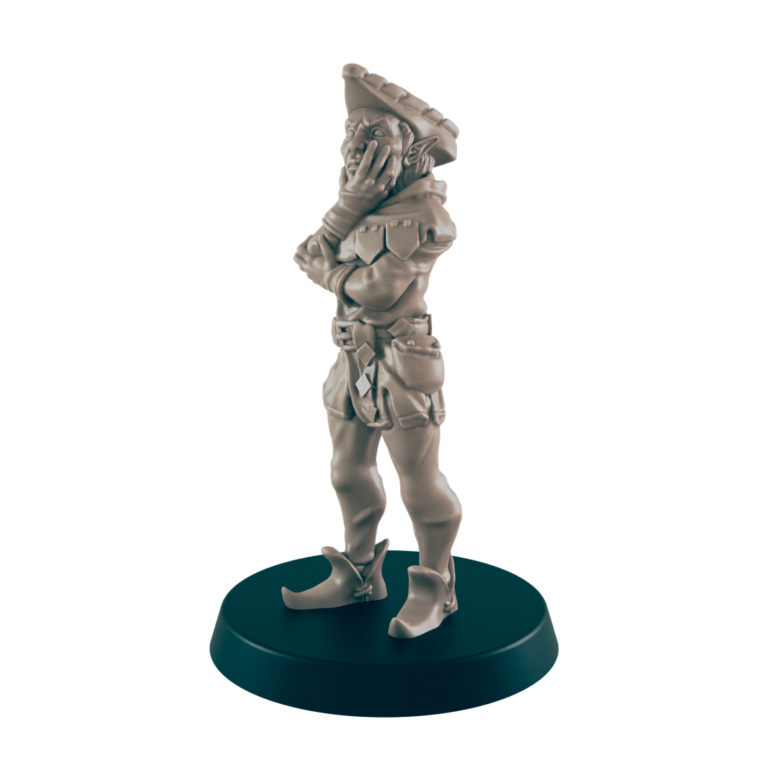 A miniature elf figurine stands pensively, hands clasped, on a dark circular base. The elf wears a hat, jacket, and breeches.