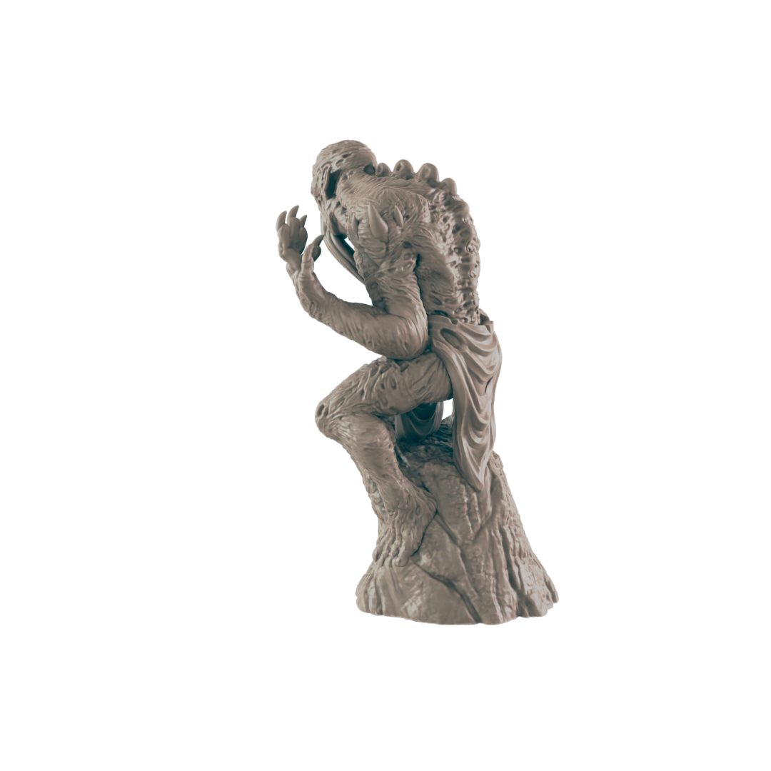 A monstrous figurine sits in a contemplative pose atop a rocky base against a dark background.