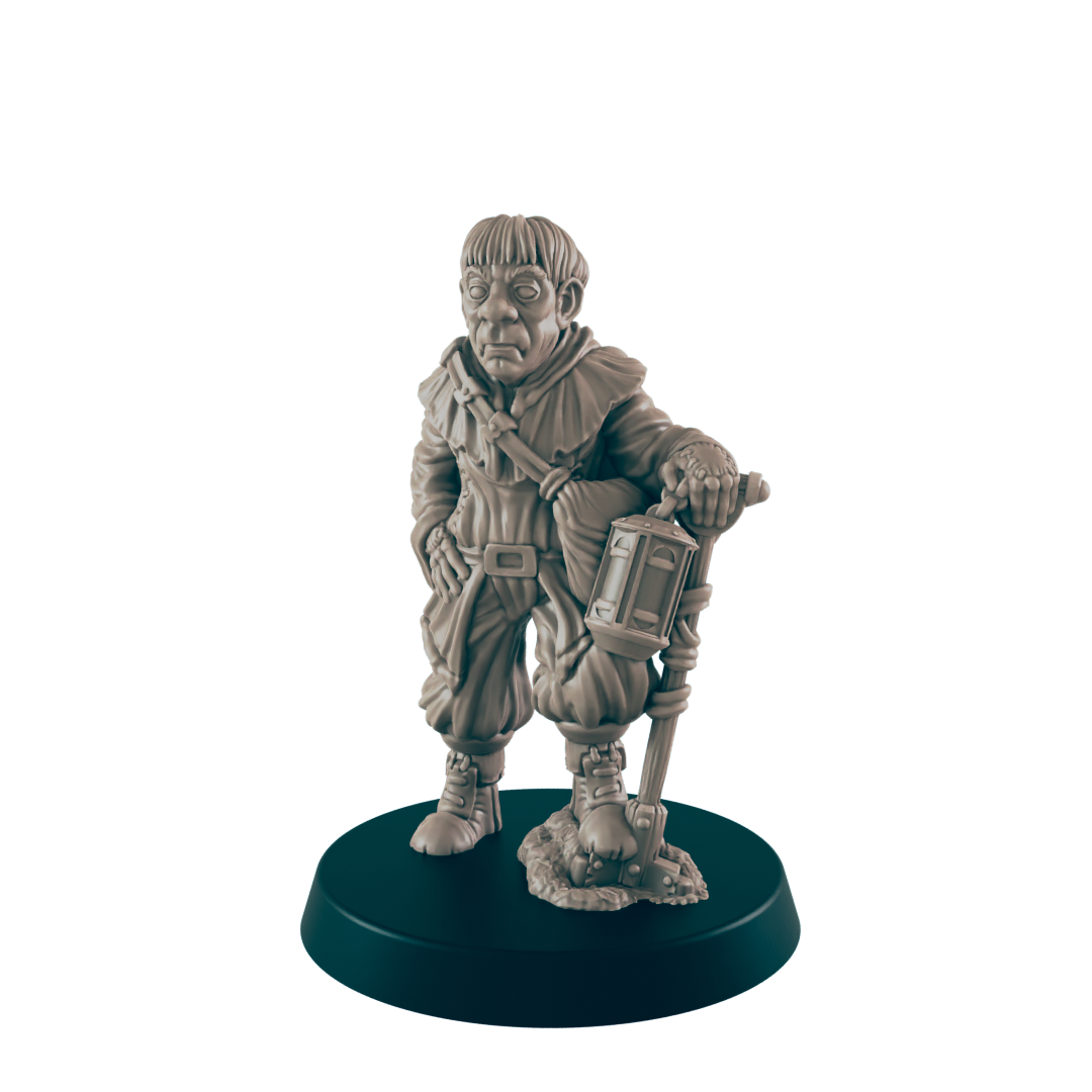 A miniature figurine of a stout, hooded figure stands holding a lantern-topped staff. The figure is posed on a dark circular base.