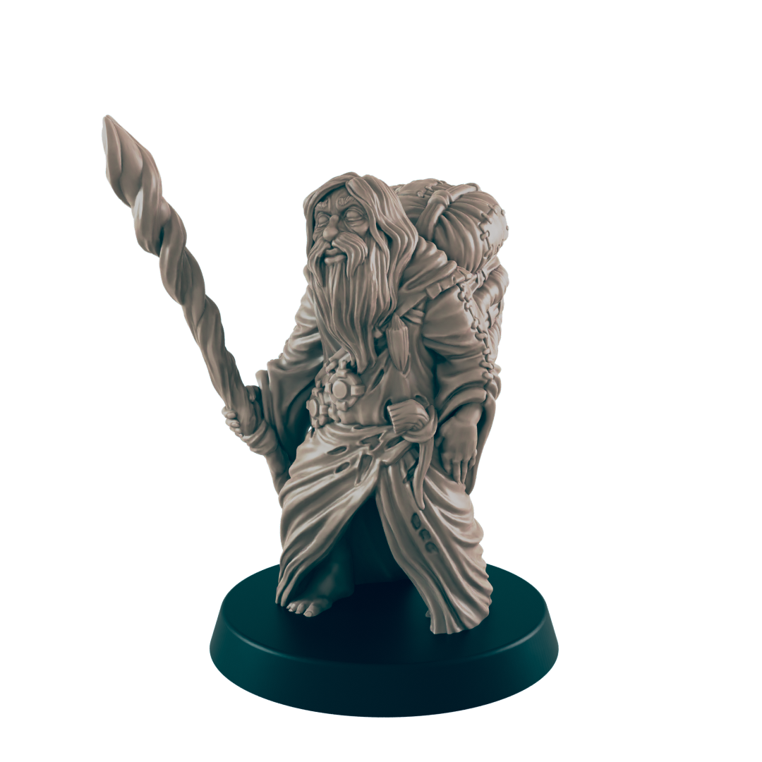 A miniature dwarf figure stands, holding a twisted staff; he wears a robe and carries a pack. The figurine is displayed on a dark circular base against a black background.
