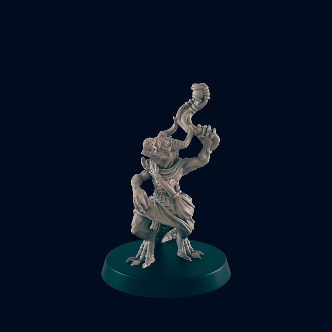 The monochrome minature figure is on a round base. It wears a small cloak around its midsection and holds an object above its head. The background is dark.