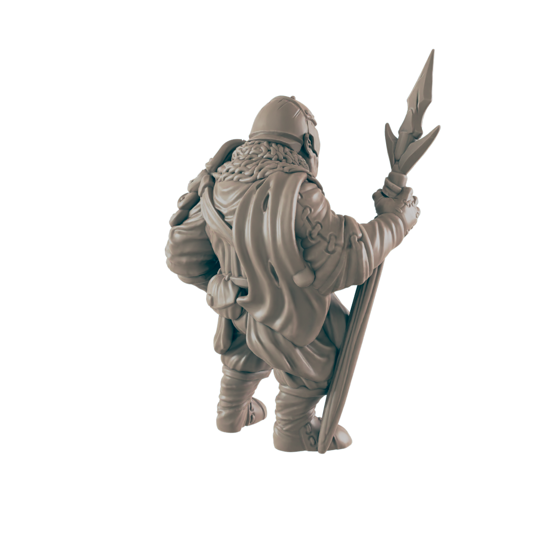 A miniature figurine of a stout, cloaked figure holds a spear-like staff. The figure stands, viewed from behind, against a plain background.