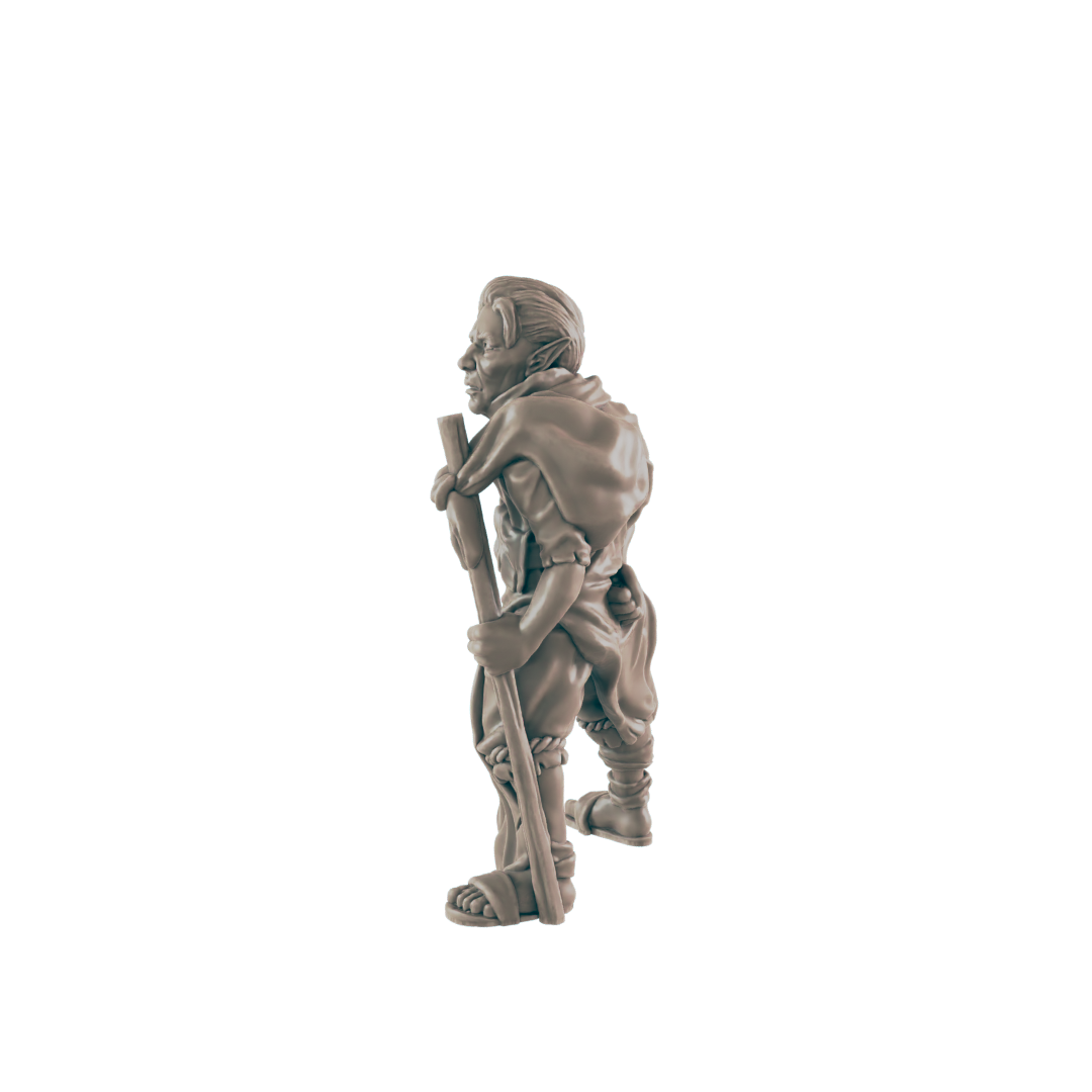 A miniature goblin figurine stands, carrying a staff, against a black background.
