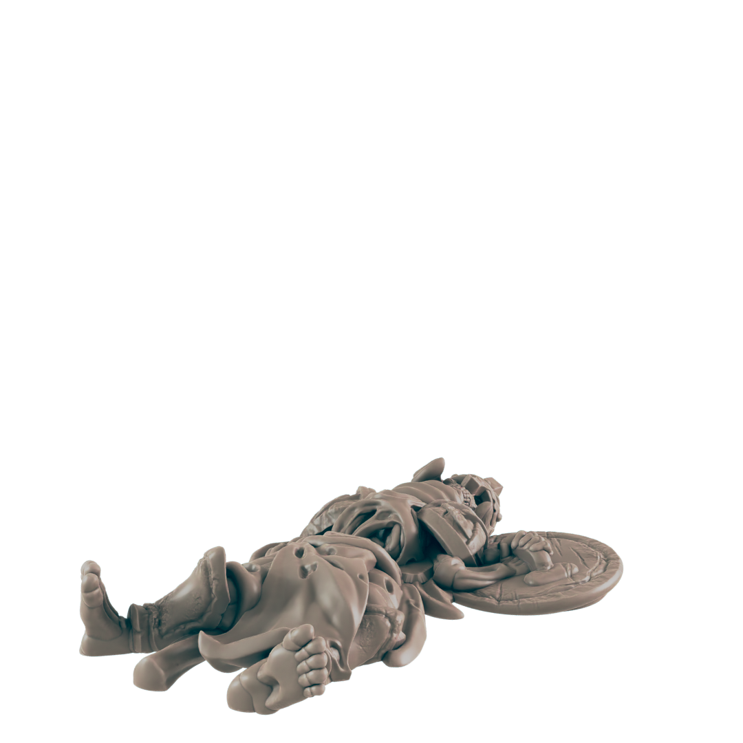 A miniature warrior lies supine; he is fallen, his shield discarded nearby, against a black background.