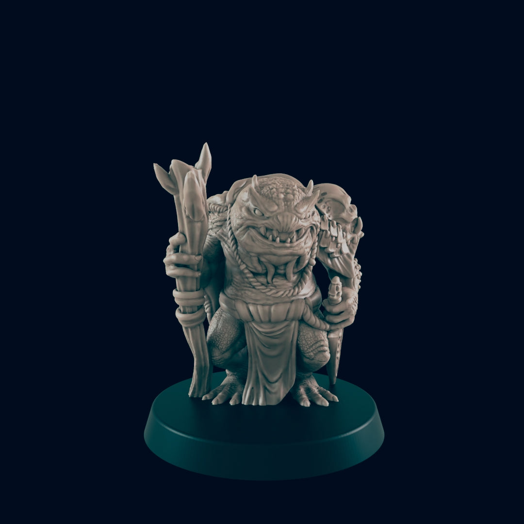 A troll-like figure clutches a staff while kneeling atop a rounded, dark teal base. The figure has reptilian features, tusks, horns, and a rope necklace on a dark teal background.