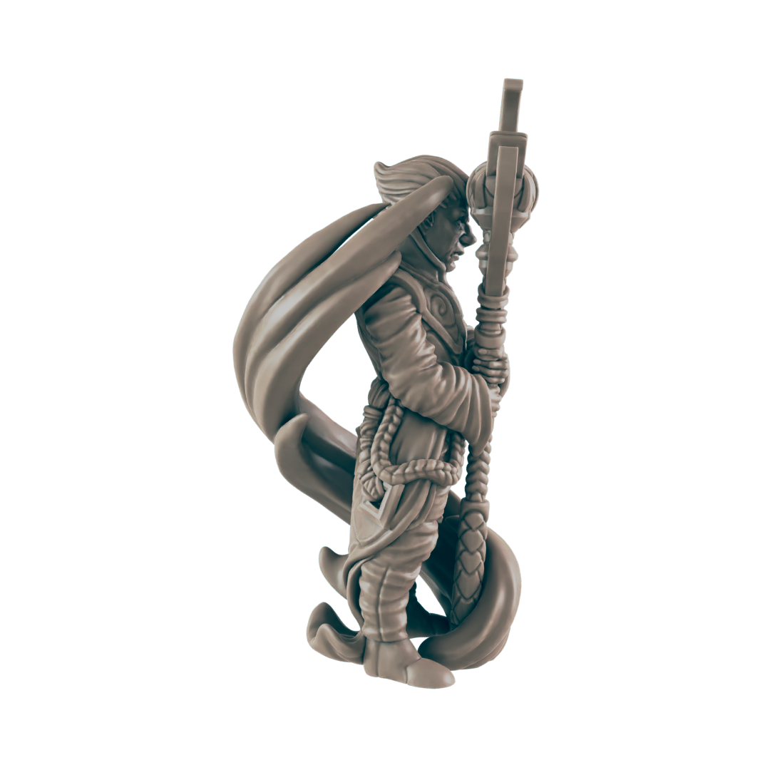 The miniature monk figure, draped with a cape, clutches an ornate staff that extends upwards. The figure is posed against a dark, flat background.