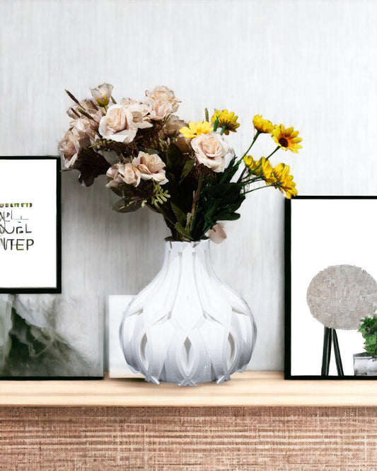 Flowers sit in a white geometric vase on a wooden shelf. Framed prints flank the vase. One text reads "QUEL STEP."
