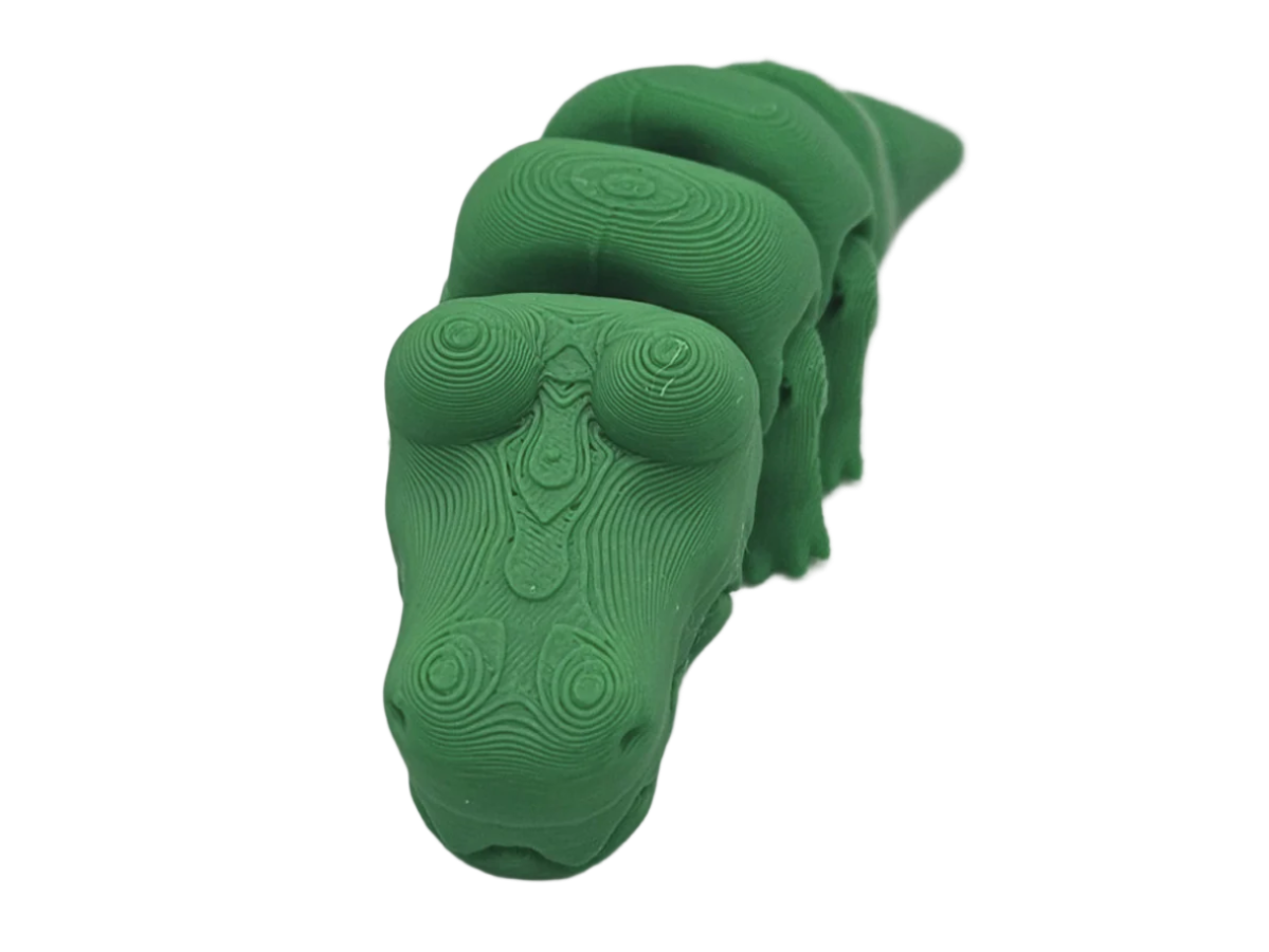A green, topographically-layered dinosaur sculpture is viewed head-on. The dinosaur has a long neck, and the scene is dark.