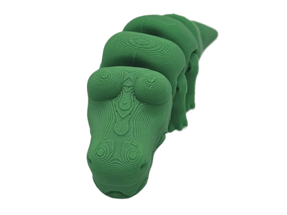 A green, topographically-layered dinosaur sculpture is viewed head-on. The dinosaur has a long neck, and the scene is dark.