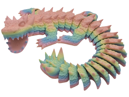 A segmented, rainbow-colored dragon toy with spikes is curled into a loop, set against a black background.
