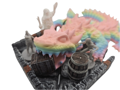 Miniatures populate a dungeon terrain: a pastel rainbow dragon head and wings, along with barrels and humanoid figures, are positioned in the setting.