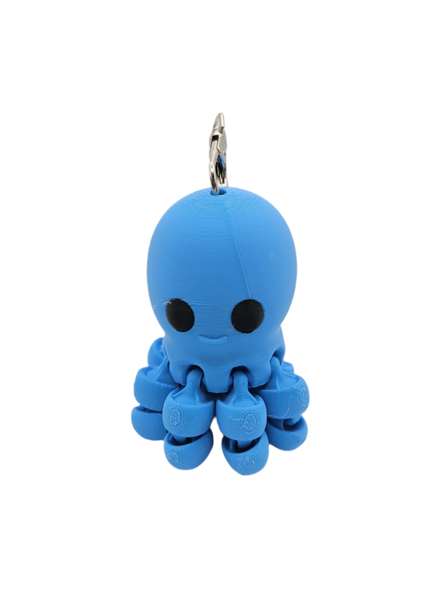 A small, blue, 3D-printed octopus keychain with black eyes and a subtle smile dangles from a silver keyring, against a black background.
