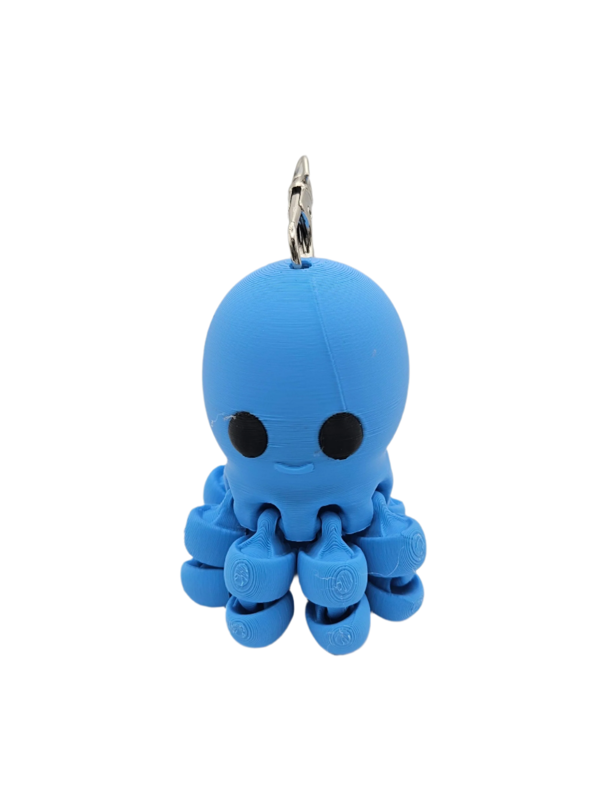 A small, blue, 3D-printed octopus keychain with black eyes and a subtle smile dangles from a silver keyring, against a black background.