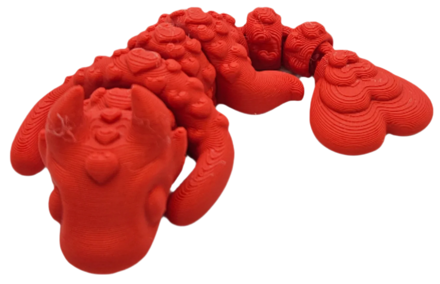 A red dragon figurine sits, showing its head, wings, and tail. The 3D-printed figure displays layer lines.