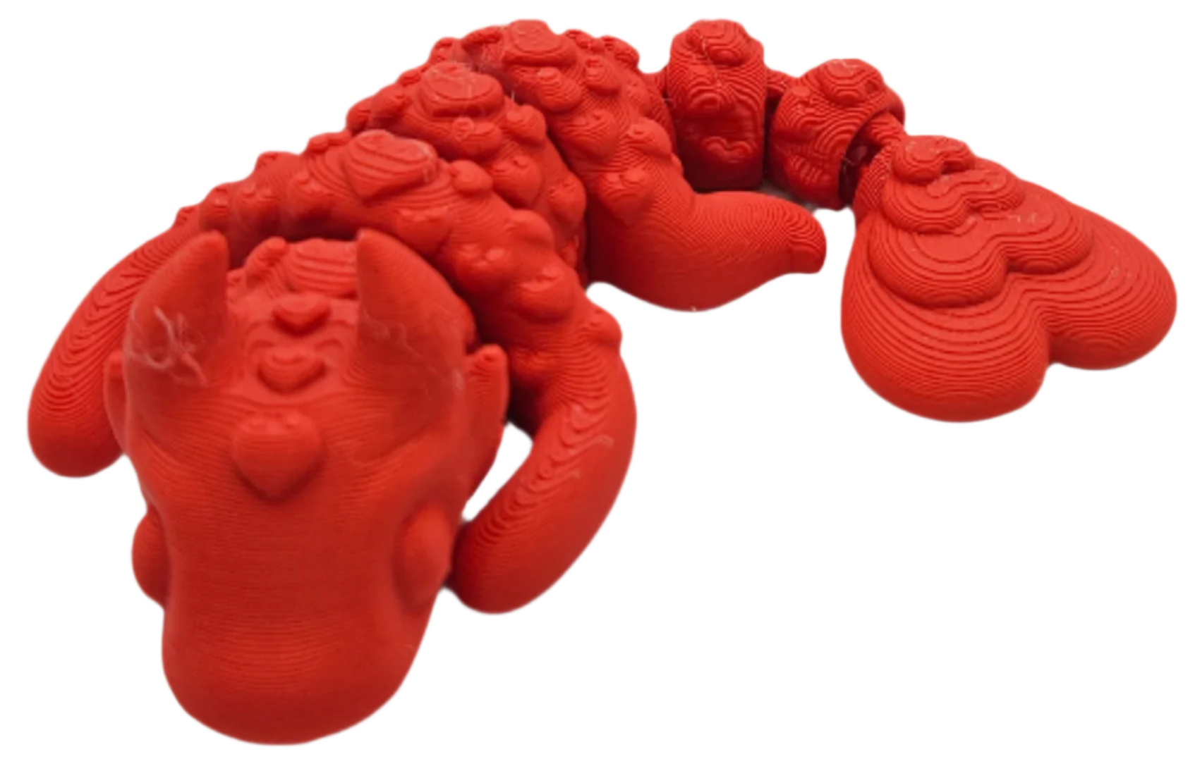 A red dragon figurine sits, showing its head, wings, and tail. The 3D-printed figure displays layer lines.