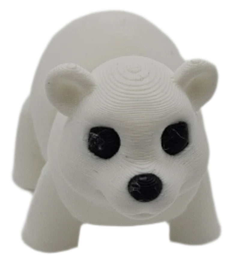 A white, 3D-printed polar bear figurine stands on a white surface. It has black eyes and a black nose.