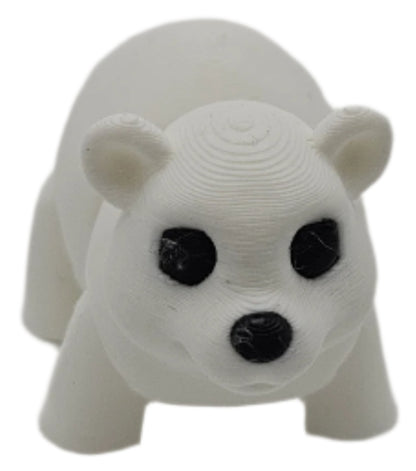A white, 3D-printed polar bear figurine stands on a white surface. It has black eyes and a black nose.