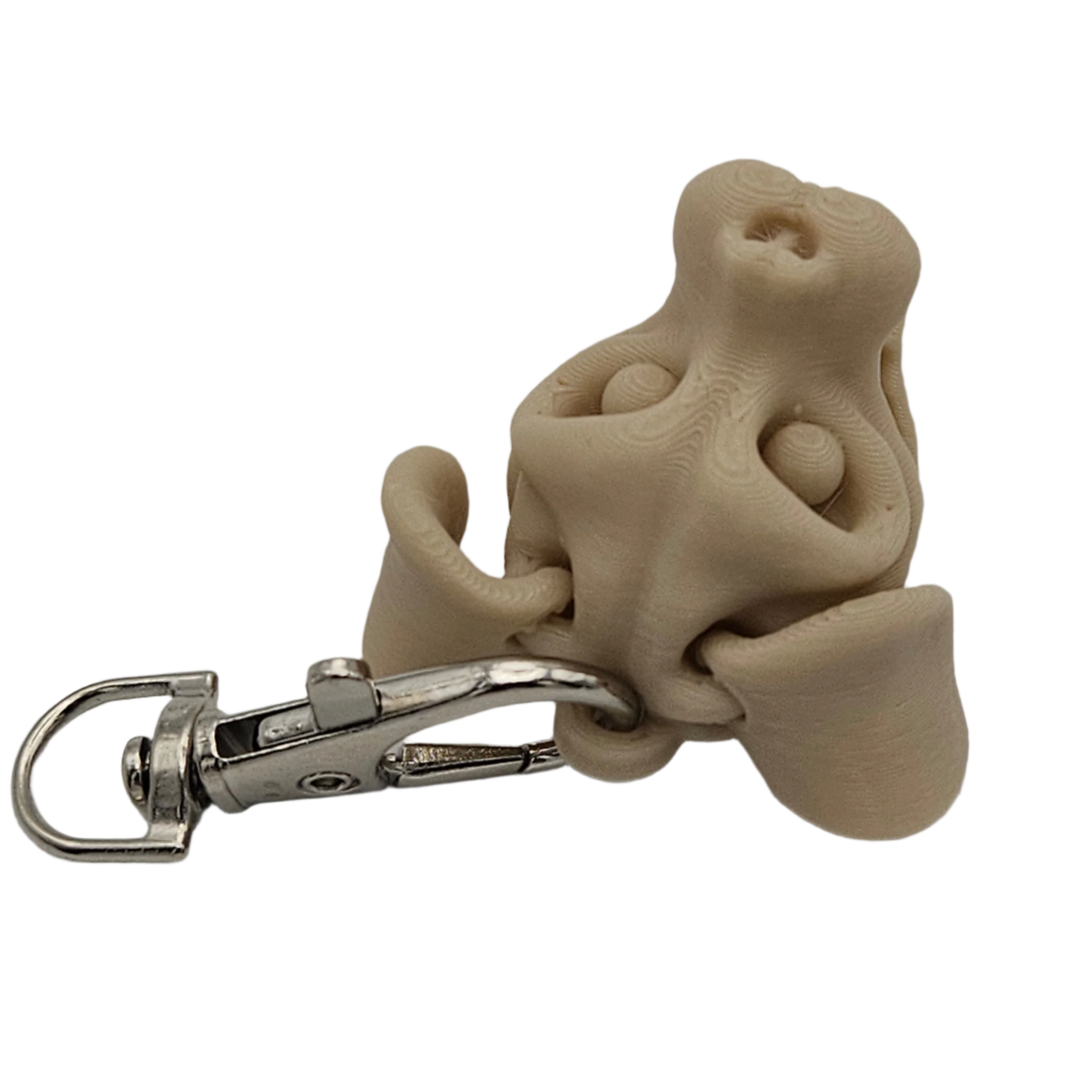 A tan, 3D-printed dog nose keychain with a silver metal clip is situated against a stark black background.