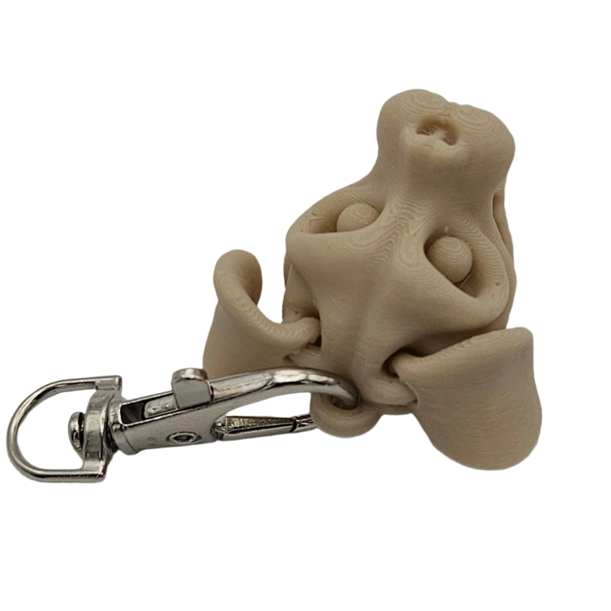 A tan, 3D-printed dog nose keychain with a silver metal clip is situated against a stark black background.