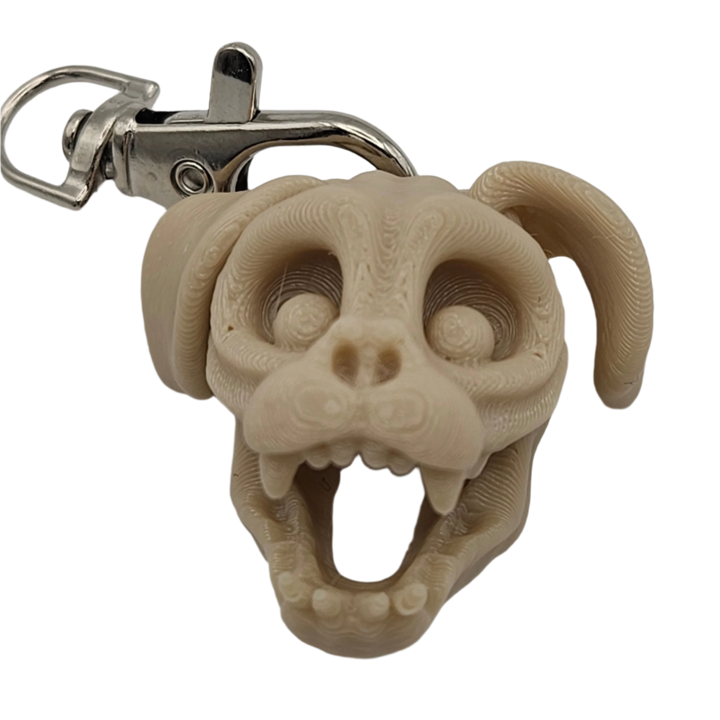 A stylized, beige dog skull keychain with a metal clip shows teeth in an open mouth. The head and ears are rounded, and its eyes are hollow.
