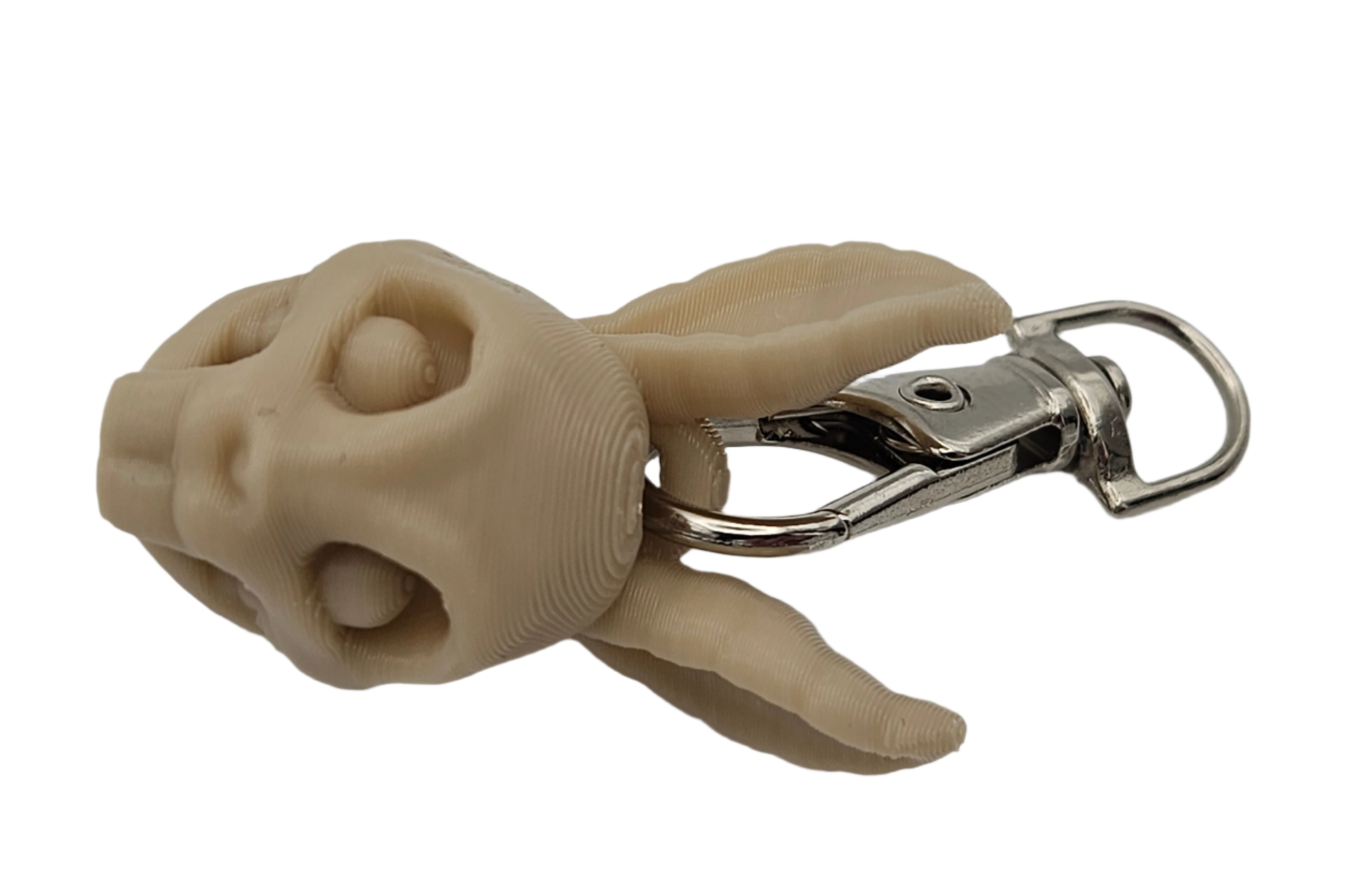 A tan, 3D-printed rabbit skull keychain lays against a solid black background, clipped with a silver swivel clasp.
