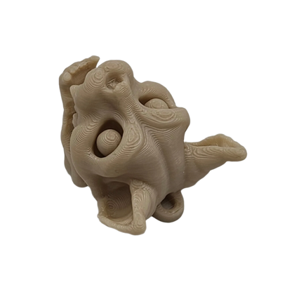 A tan, topographically textured sculpture of a distorted, dragon-like head is centered in the frame, with a gaping mouth, bulbous eyes, and flowing ear-like forms, against a solid black background.