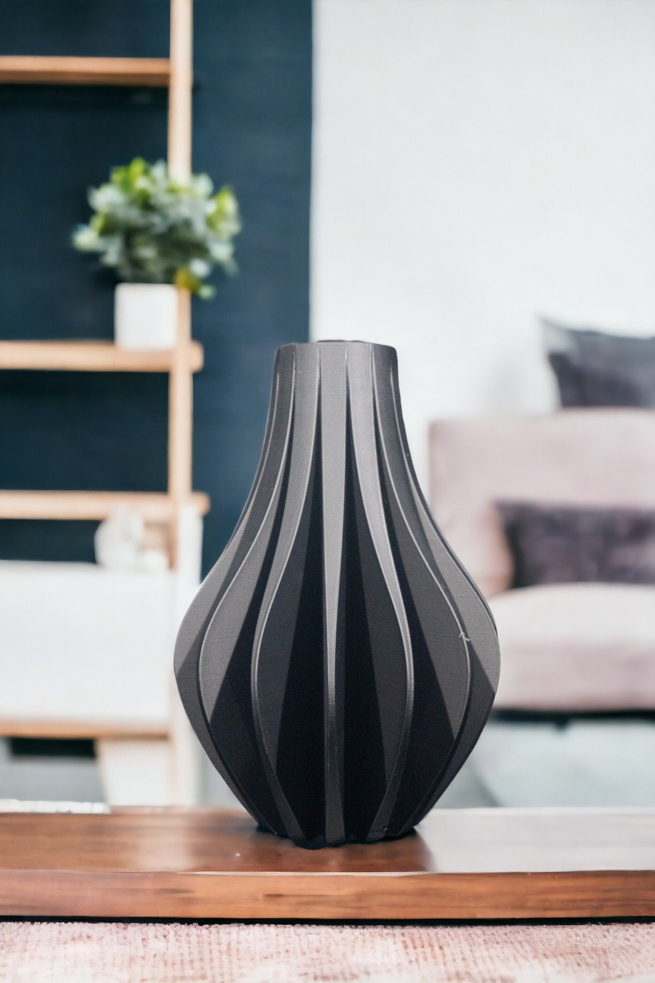 A decorative, gray vase sits centered on a wood tray. A navy wall with a plant on a shelf and a light-colored couch fill the blurred background.