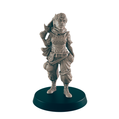 A miniature female figure, standing and holding a weapon, is displayed on a dark circular base.  She wears a hooded top and loose trousers with pouches.