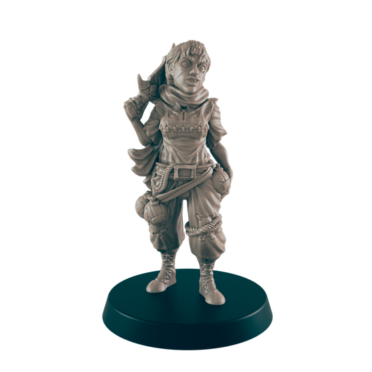 A miniature female figure, standing and holding a weapon, is displayed on a dark circular base.  She wears a hooded top and loose trousers with pouches.