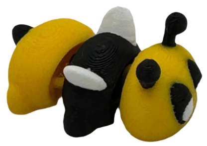 Three small, 3D-printed figures stand together: one half-yellow with black details, one mostly black with white, and one rounded yellow with black spots. They are on a solid black background.
