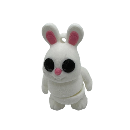 A white 3D-printed rabbit figurine stands on a black surface. The bunny has pink inner ears and a pink nose with large black eyes.