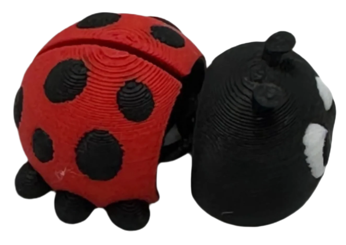 Two plastic ladybugs, one red with black spots and one black with white spots, rest beside each other against a black background.