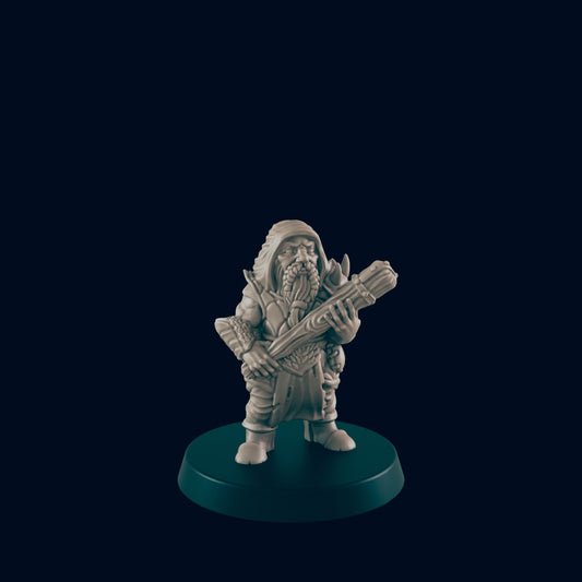 A miniature dwarf figure stands holding a bundle of wood, posed on a black base. The background is solid black.