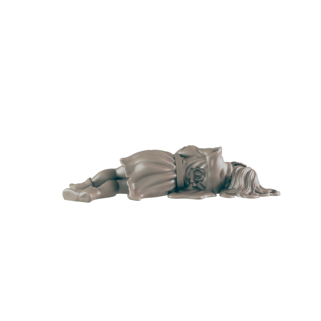 A statue of a child in a dress with a flower on the chest lies face down on a black surface.