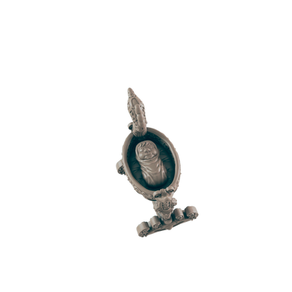 A statuette features a baby sleeping in a highly ornamented oval cradle which is attached to a base in a dark blue, monochrome setting.