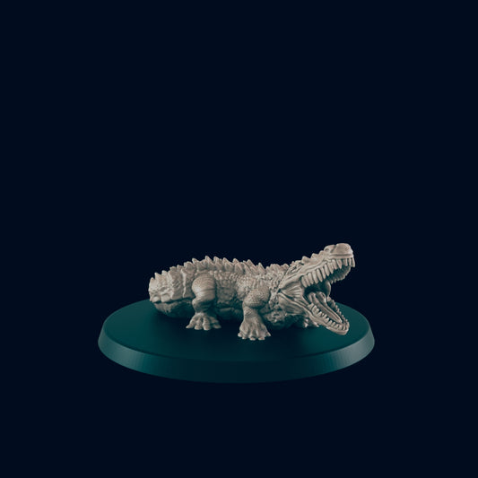 A monochromatic alligator miniature sits on a small, flat, round, teal base. The alligator's mouth is open wide, revealing many teeth. The background is a solid dark teal.