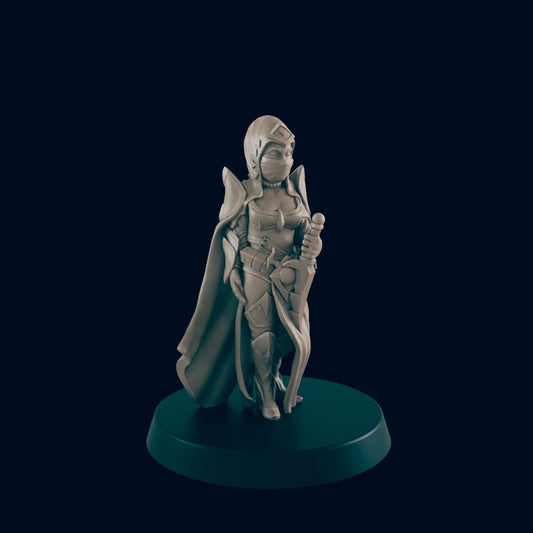 A miniature figure stands on a base, holding a sword at her side. She wears a cape, hood, and mask in a dark, blank space.