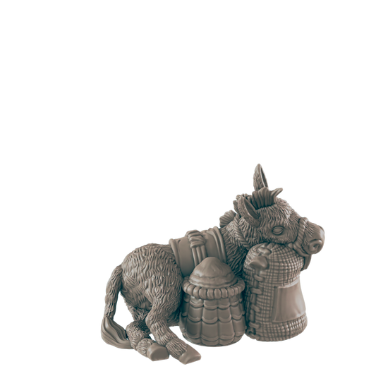 A donkey figurine rests against two sacks; one woven, one barrel-shaped, against a dark background.