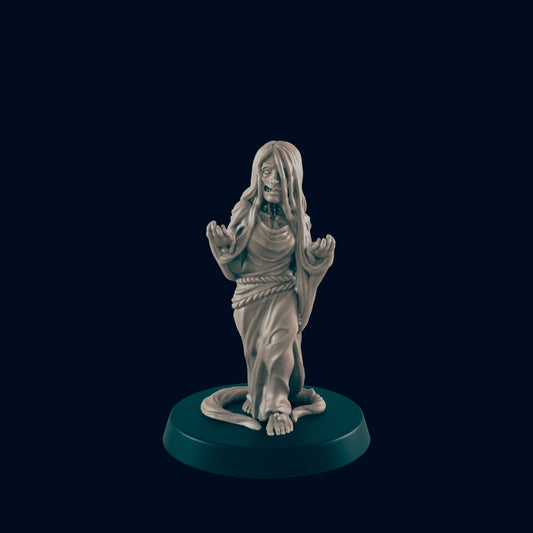 A miniature female figure, appearing ghostly and disheveled, stands on a circular base against a dark background.  The figure's hands are raised.