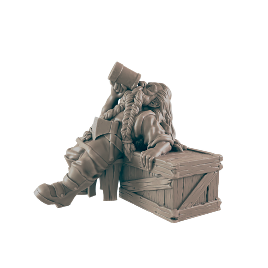 A monochrome dwarf figurine is slumped over a wooden crate, drinking from a tankard. Her braids are long and thick, and she is wearing boots, a tunic, and an axe across her chest.
