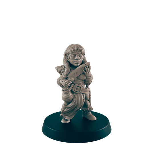 A female miniature figurine, holding a knife, stands on a dark circular base against a black background.