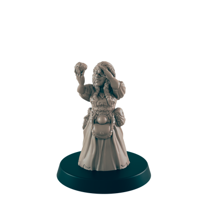 A miniature female figurine, holding up a small object and shielding her eyes, stands on a dark circular base.