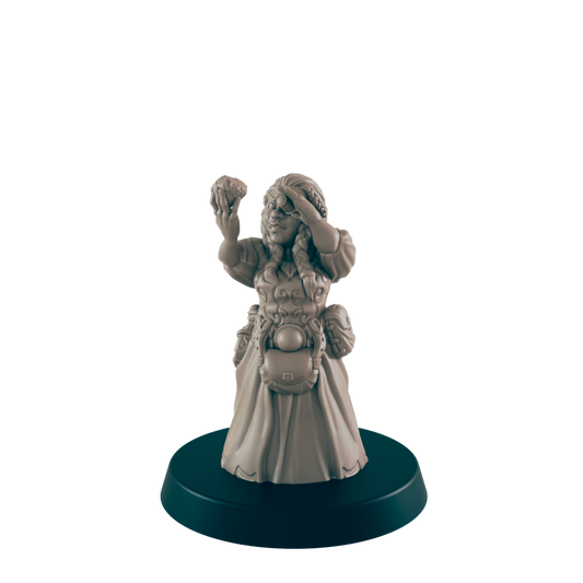 A miniature female figurine, holding up a small object and shielding her eyes, stands on a dark circular base.