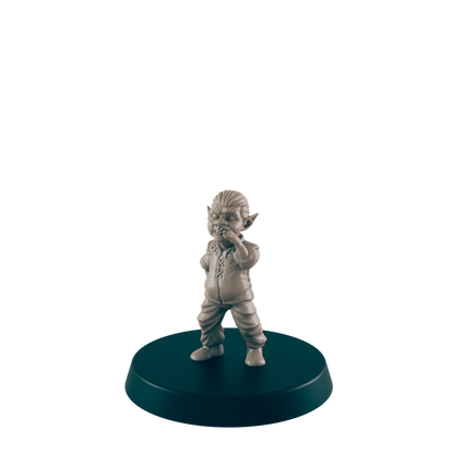 A small, tan goblin figurine stands on a dark circular base, covering its mouth, seemingly in contemplation or amusement against a plain dark background.