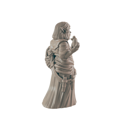 A miniature figurine of a gnome, wearing a robe and holding an object, stands against a black background.