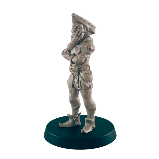 A miniature elf figurine stands pensively, hands clasped, on a dark circular base.  The elf wears a hat, jacket, and breeches.