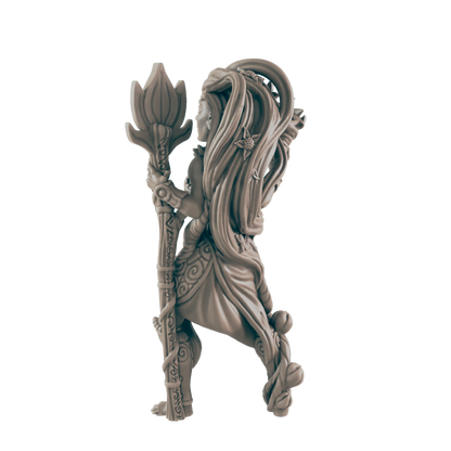 A gray, uncolored figurine of a lithe woman stands, holding a tall staff topped with a lotus-like flower. Vines and floral patterns adorn her body and the staff, on a white background.